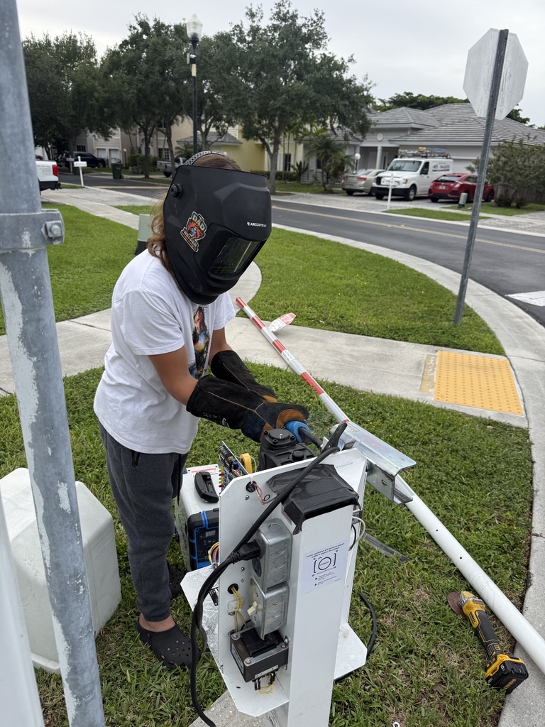 Technician wearing protective equipment servicing the open interior of an outdoor access-control cabinet